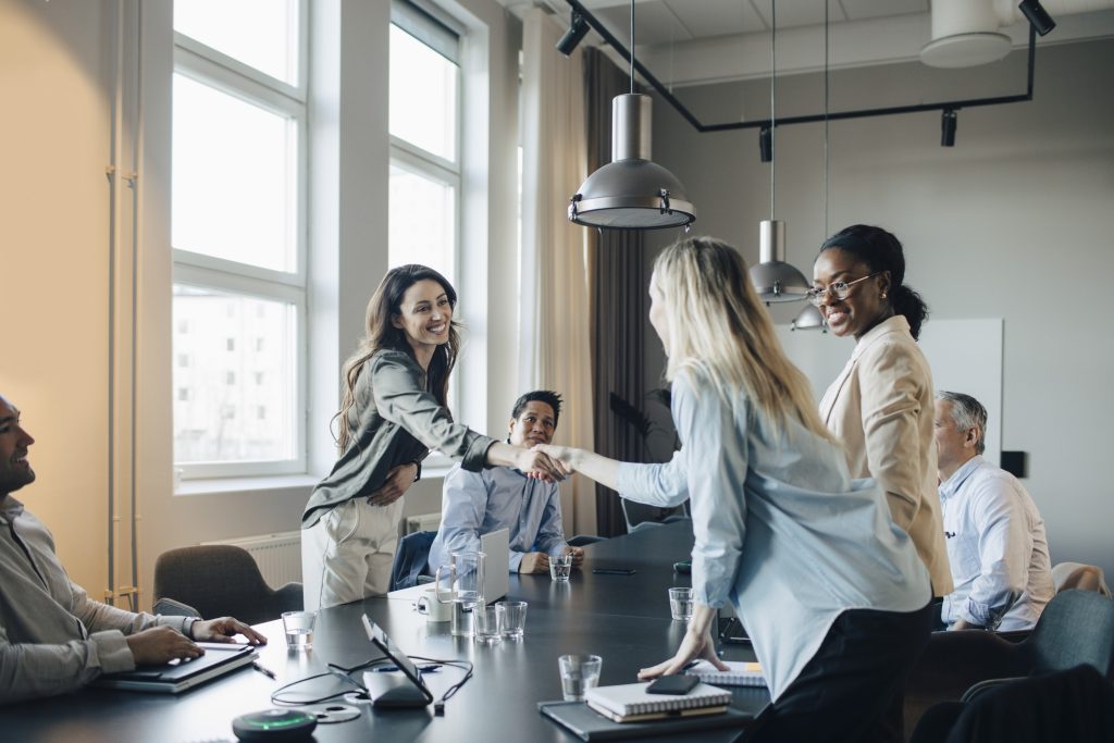 Smiling businesswoman shaking hand and greets client during meeting in office