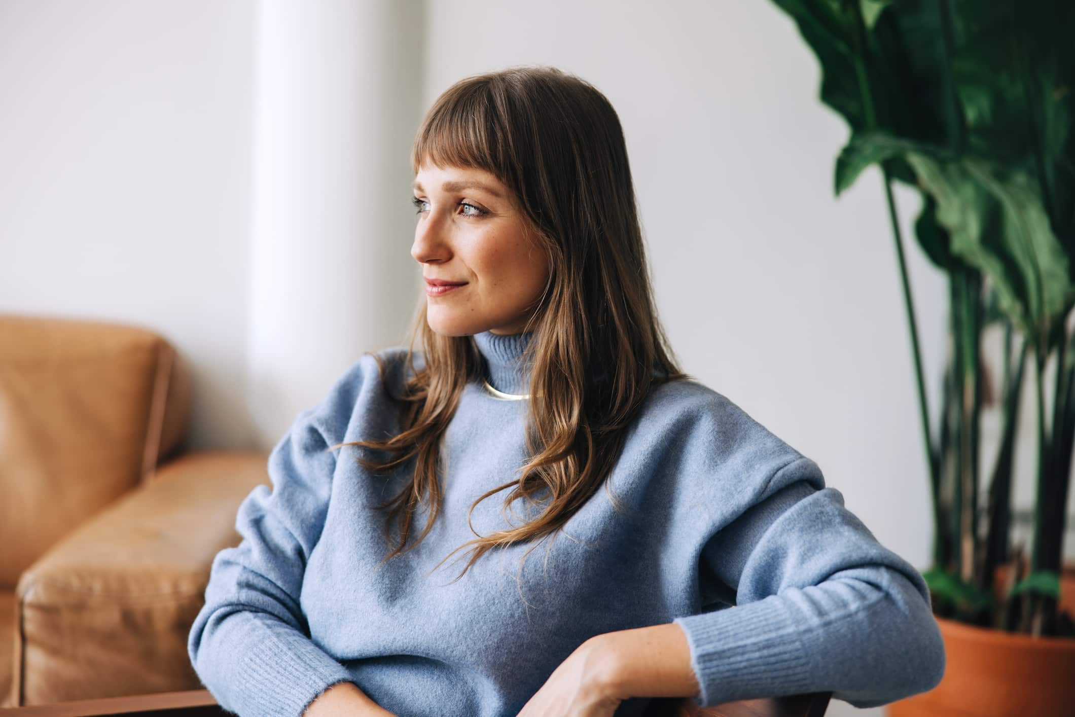 Young businesswoman looking away thoughtfully while sitting in a modern office. Young female entrepreneur contemplating new business in an office lobby.