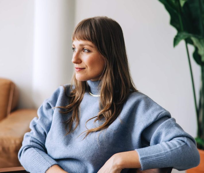 Young businesswoman looking away thoughtfully while sitting in a modern office. Young female entrepreneur contemplating new business in an office lobby.