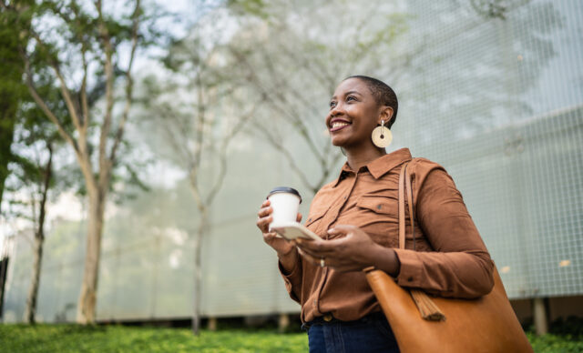 Business woman holding smartphone and looking away outdoors