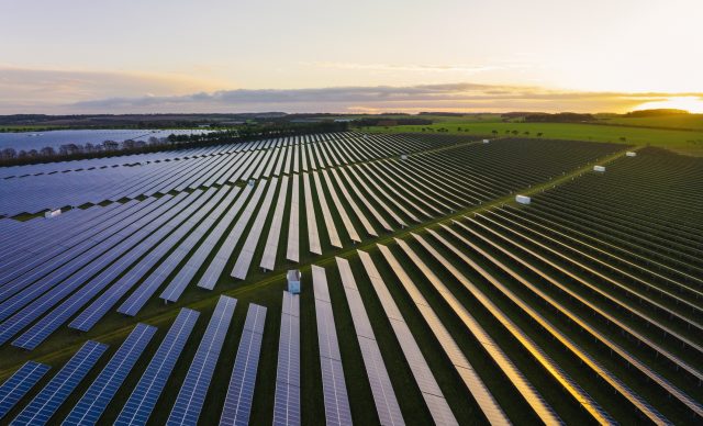 Abstract aerialdrone view over a field of solar panels at sunrise