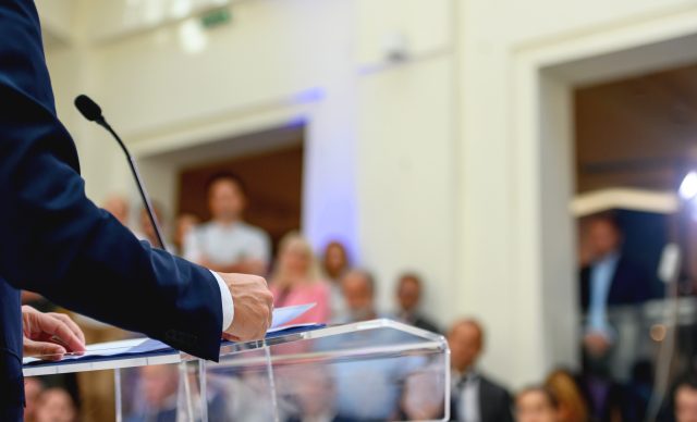 Unrecognizable politician speaking publicly from the lectern