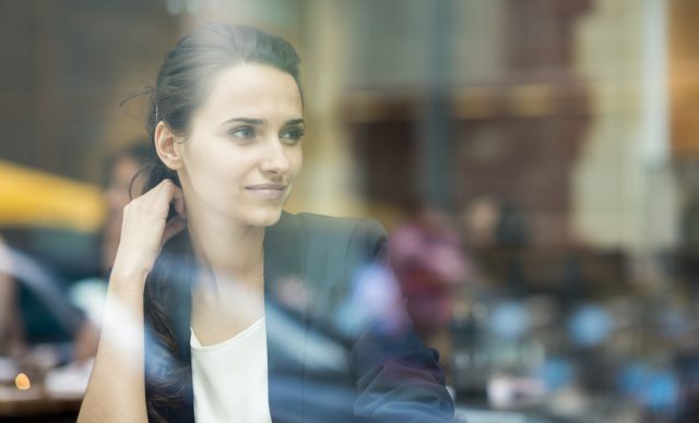 Young businesswoman looking out of cafe window, London, UK