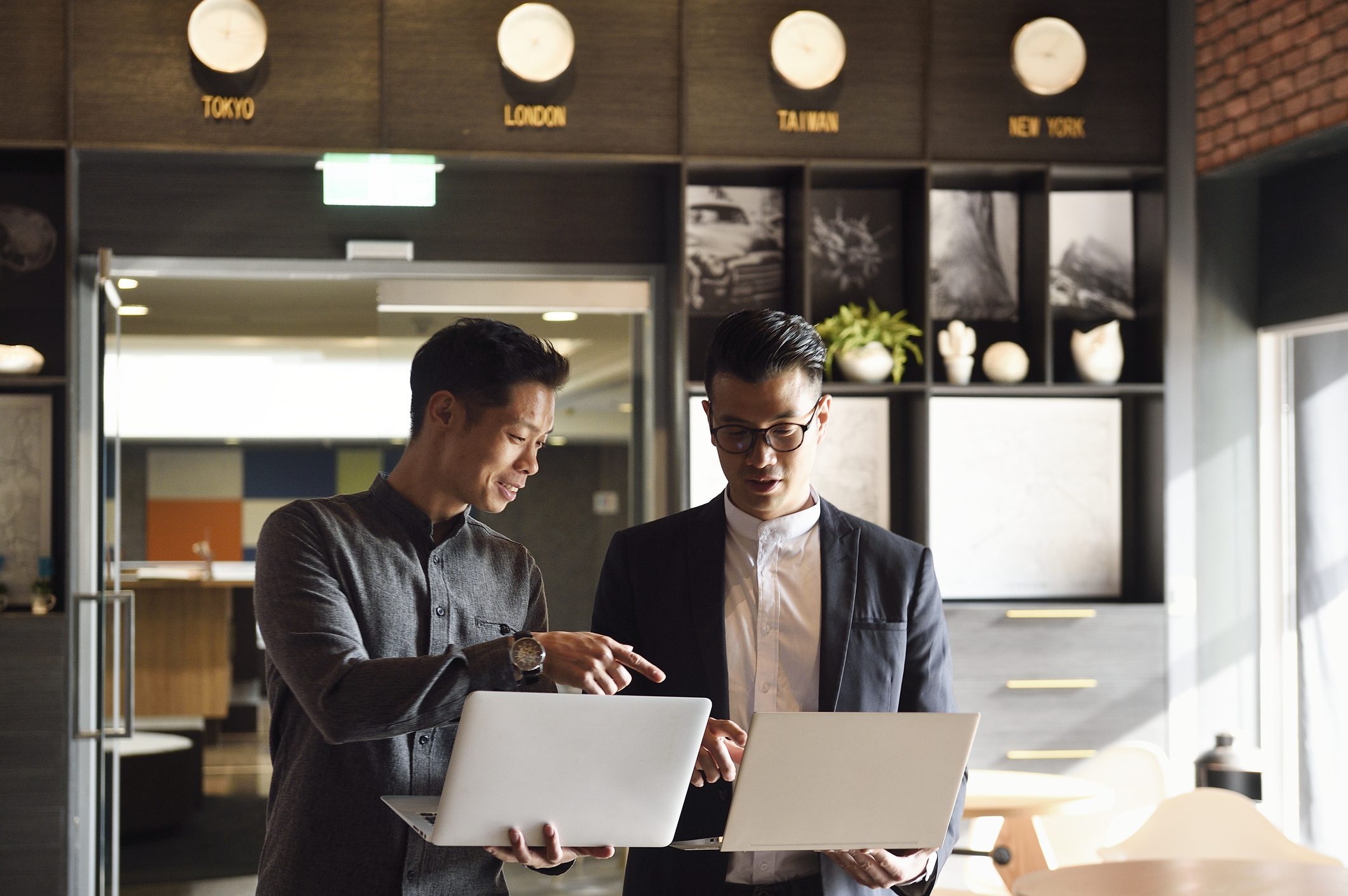 Two handsome Chinese men standing with laptops in an office