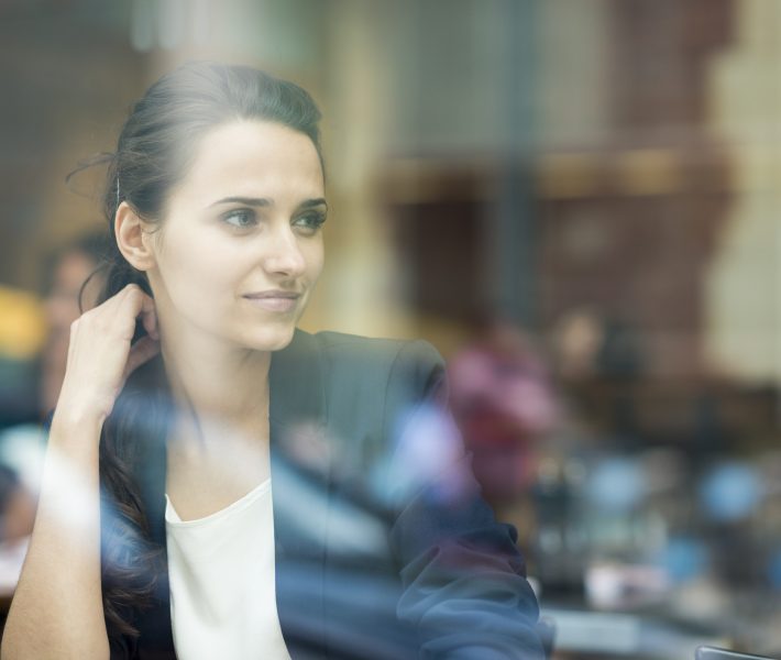 Young businesswoman looking out of cafe window