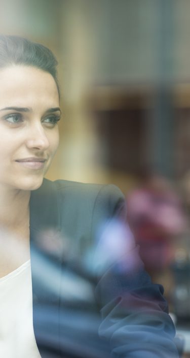 Young businesswoman looking out of cafe window