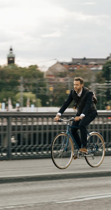 Businessman riding bicycle on street in city against sky