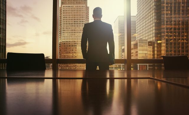 Silhouette of businessman looking out at financial district