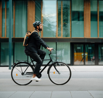 Side view of a city commuter riding to work on a bicycle. Young single businessman traveling from work to home on a bike, wearing a backpack and helmet for safety. City lifestyle of single man.