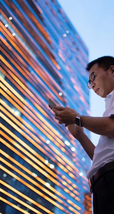 A young Asian businessman wearing a white shirt is using a smartphone