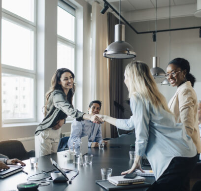 Smiling businesswoman shaking hand and greets client during meeting in office