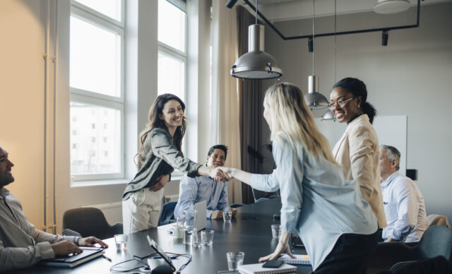 Smiling businesswoman shaking hand and greets client during meeting in office