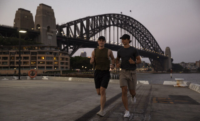 A shot of two young, Caucasian males running along Sydney Harbour, Australia.