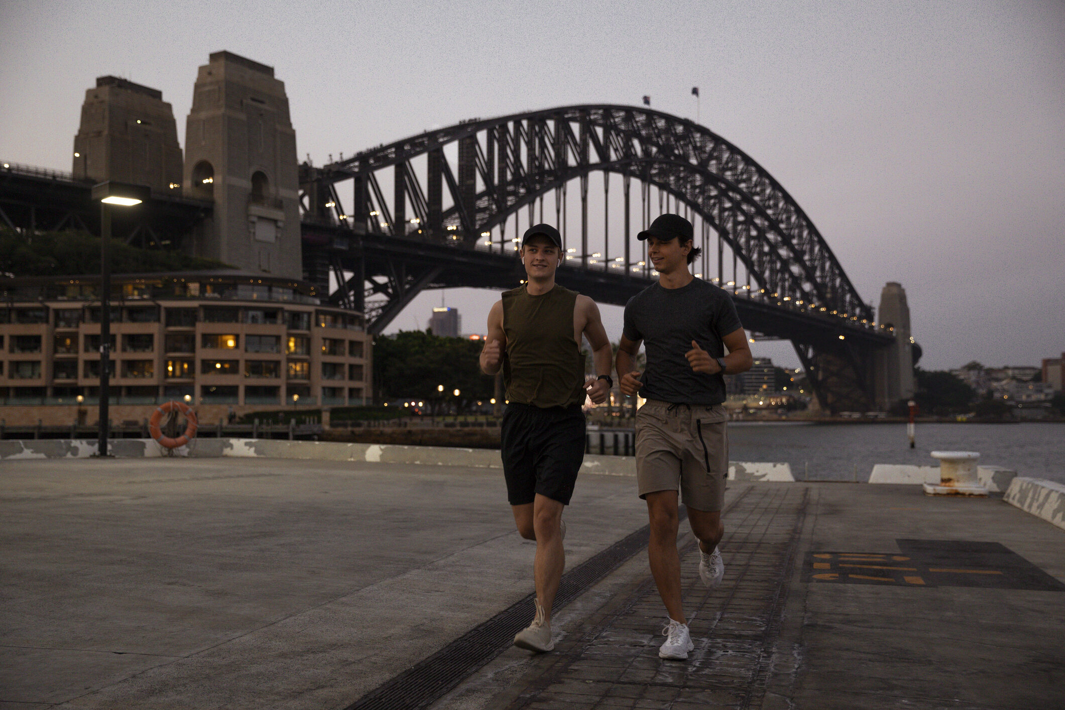 A shot of two young, Caucasian males running along Sydney Harbour, Australia.